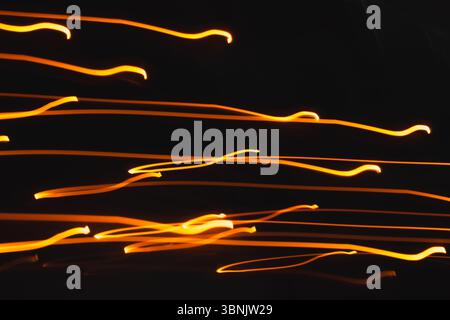 Abstrakter heller Hintergrund mit leuchtenden orangefarbenen Linien, die sich anmutig über einen dunklen Hintergrund winden und ein Gefühl dynamischer Bewegung erzeugen Stockfoto