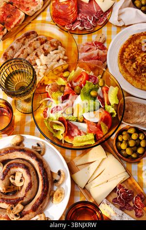 Ein lebhafter Tisch mit einem traditionellen katalanischen Salat, Botifarra mit Pilzen, Oliven, spanischer Marmelade, Käse, und eine Tortilla mit Kartoffeln Stockfoto