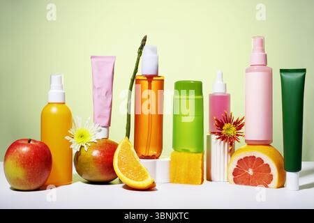 Eine lebendige Kollektion veganer Hautpflegeprodukte mit frischem Obst und Blumen auf einer minimalistischen Bühne. Perfekt für umweltbewusste, gesundheitsorientierte Stockfoto