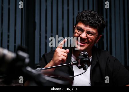 Eine lebhafte Podcast-Aufnahmesitzung in einem modernen Studio, bei der ein Lautsprecher über ein professionelles Mikrofon Einblicke teilt und ein Live A anspricht Stockfoto