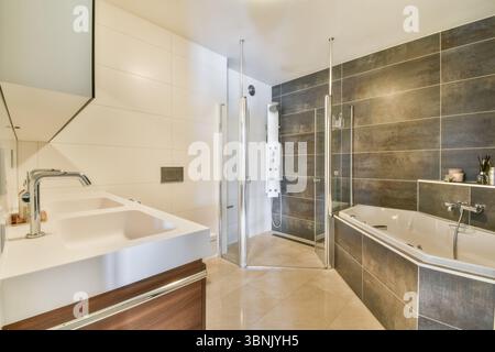 Luxuriöses Badezimmer mit elegantem Design mit zwei Waschbecken, Glasdusche und stilvoller Badewanne. Der Raum kombiniert moderne Fliesen mit elegantem Fixtu Stockfoto