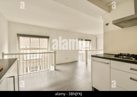 Helle, moderne Küche mit elegantem Design und viel Tageslicht durch große Fenster. Mit modernem Schrank, perfekt für kulinarische Enthusiasten Stockfoto