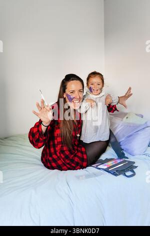 Ein freudiger Moment zwischen Mutter und Tochter, während sie zu Hause zusammen spielen, beide hell lächeln. Die Szene fängt die Wärme und Verbundenheit der fami ein Stockfoto