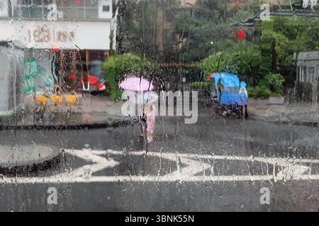 CHENGDU, CHINA - 3. JULI 2025 - Fußgänger reisen am 3. Juli 2025 im Regensturm in Chengdu, Provinz Sichuan, China. Stockfoto