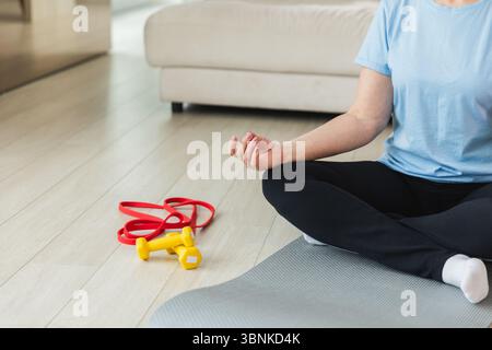 Yoga-Achtsamkeitsmeditation. Ältere reife Frau, die zu Hause Yoga praktiziert. Hände in Kinnmudra-Geste. Erwachsene alte Dame sitzt in Lotusposition und Meditation entspannend. Frau, die Atemübungen macht Stockfoto