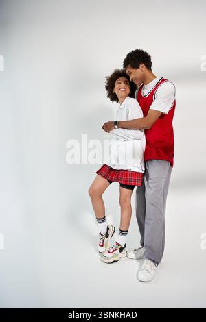 Liebevolles Paar, das modisch gekleidet ist, eine verspielte Umarmung genießt und gleichzeitig Erinnerungen schafft. Stockfoto
