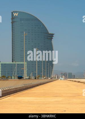 Ein Blick auf das beeindruckende W Hotel (Hotel Vela) vom leeren Moll de Llevant in Barcelona, der starke Linien und Perspektiven schafft. Stockfoto