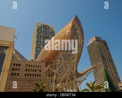 Ein flacher Blick auf Frank Gehrys goldene Skulptur „Peix“, eingerahmt von den modernen Wolkenkratzern des Hotels Arts und des Torre Mapfre Barcelona. Spanien. Stockfoto