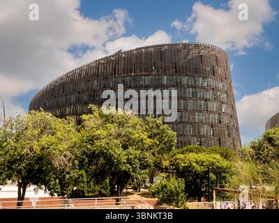 Hinter grünen Bäumen erhebt sich die geschwungene Form des Gebäudes des Barcelona Biomedical Research Park, ein Beispiel für zeitgenössische Architektur. Spanien. Stockfoto