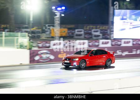 Motion Blur Drag Racing bei Nacht, bei dem Autos auf der Rennstrecke mit Zuschauern in der Nähe konkurrieren Stockfoto
