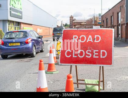 Nahaufnahme eines roten „ROAD CLOSED“-Schilds in einem britischen Stadtzentrum, das Fahrer vor Straßensperrungen bei Baustellen warnt. Stockfoto