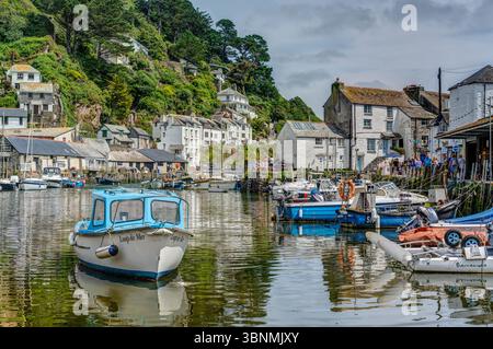 Hochwasser im Hafen von Polperro, mit kleinen Fischerbooten und Tendern, die von den umlaufenden Dorfgebäuden betrachtet werden, wunderschön und charmant. Stockfoto