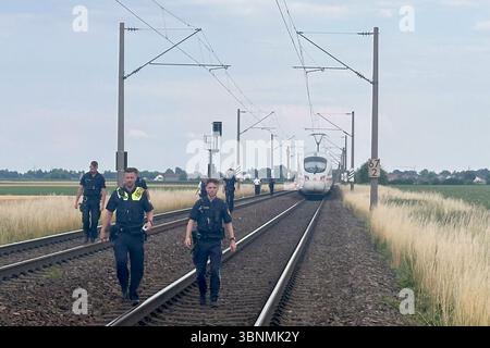03. Juli 2025, Bayern, Straßkirchen: Polizeibeamte gehen durch das Gleisbett vor einem ICE-Zug, bei dem ein Mann mehrere Fahrgäste in Niederbayern attackierte. Der mutmaßliche Täter wurde verhaftet. Er hatte gefährliche Gegenstände bei dem Angriff benutzt. Foto: Ute Wessels/dpa Stockfoto