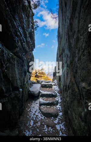 Steintreppen, die mit Schnee bedeckt sind, führen durch eine enge Schlucht zu einem hellen Himmel Stockfoto