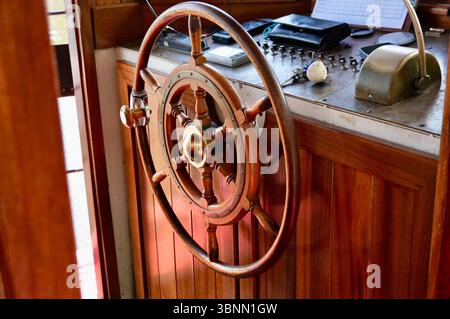 Hölzernes Schiffsrad auf einer Touristenfähre. Braunes Rad. Kabine des Fährkapitäns Stockfoto