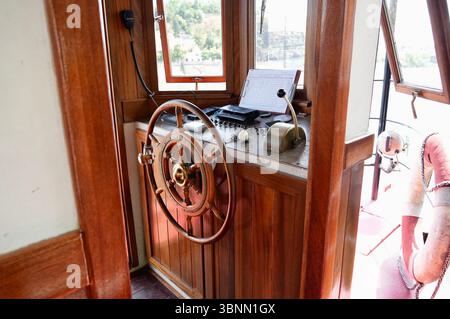 Hölzernes Schiffsrad auf einer Touristenfähre. Braunes Rad. Kabine des Fährkapitäns Stockfoto