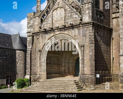 Locronan, Frankreich – 21. Mai 2025: Nahaufnahme der bogenförmigen Steinhalle und des Haupteingangs der Kirche Saint-Ronan in Locronan, Finistère, Bretagne, Buil Stockfoto