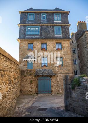 Saint-Malo, Frankreich – 17. Mai 2025: Traditionelles Stadthaus aus Stein mit Schieferdach und blauen Fensterläden in der historischen ummauerten Stadt, das das klassische Breto widerspiegelt Stockfoto