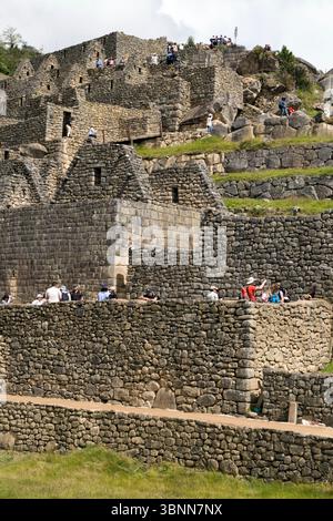 Touristen in den Ruinen von Machu Picchu, der Inka-Zitadelle aus dem 15. Jahrhundert in Peru, die oft als „verlorene Stadt der Inka“ bezeichnet wird. Stockfoto
