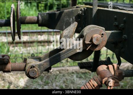 Rostige Zughakenkupplung mit großem mechanischen Drehzapfen, Sicherungsstift, Metallfedern und korrodierten Oberflächen, fotografiert im Freien auf Eisenbahngleisen Stockfoto