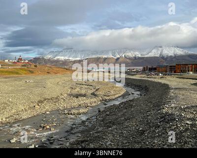 Eine wunderschöne Aussicht auf Berge, einen Fluss und Gebäude unter dem bewölkten Himmel. Longyearbyen Svalbard Stockfoto