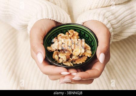 Walnüsse in einer kleinen Schüssel. Frau mit gesundem Nuss-Snack. Nahaufnahme natürlicher Lebensmittel. Braune Nüsse zum Essen oder Backen. Proteinquelle mit Vitaminen. Stockfoto