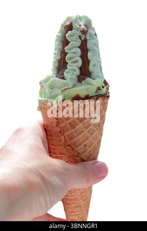 Frauenhand hält Waffelkegel mit Pistazien und Schokoladeneis auf weißem Hintergrund. Stockfoto