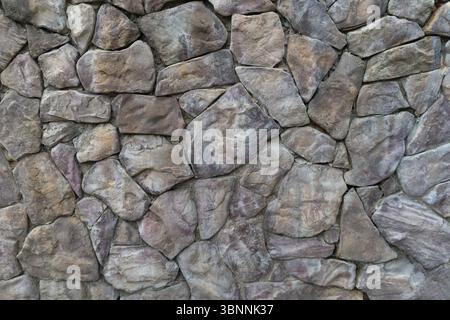 Kopfsteinpflasterwand aus Steinen unterschiedlicher Größe und Form. Steinwandstruktur. Natürliche Kopfsteinmauer als Hintergrund. Stockfoto