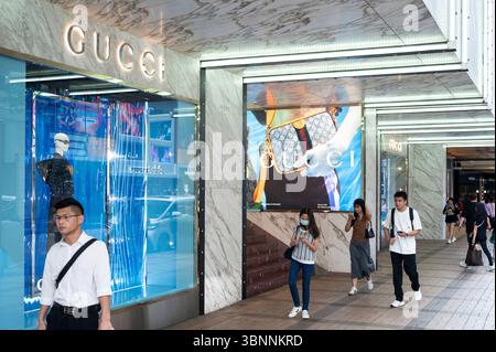 Shopper laufen am italienischen Luxusmodemarke Gucci-Logo vorbei und laden in Hongkong ein. Stockfoto