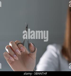 Elegante beige Maniküre, die mit einer Schere perfektioniert wird, professionelle Nageltechniker aus der Nähe Stockfoto