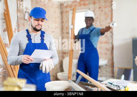 Vorarbeiter unzufrieden mit der Qualität der Reparaturarbeiten des männlichen Bauherrn Stockfoto