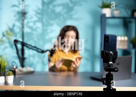 Nahaufnahme des Telefons, das von einer Frau benutzt wurde, die von einem Partnerverlag gesponsert wurde, um neue Inhalte für das Auspacken von Büchern zu erstellen. Konzentrieren Sie sich auf das Smartphone, das von Influencer verwendet wird, um neue Autoren für die Produktplatzierung zu verwenden Stockfoto