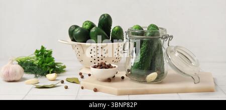 Zusammensetzung mit frischen Gurken zur Konservierung auf hellem Hintergrund Stockfoto