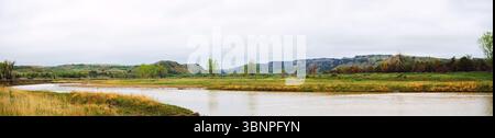 Eine breite Kurve im Little Missouri River durchquert goldene Graslandschaften im Theodore Roosevelt National Park. Bewölkter Himmel hebt die Ebene hervor. Stockfoto