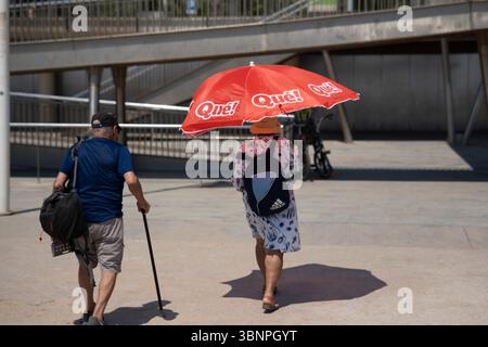 Barcelona, Spanien. Juli 2025. Touristen schützen sich vor der Sonne unter einem Sonnenschirm am Strand von Barcelona. Quelle: SOPA Images Limited/Alamy Live News Stockfoto