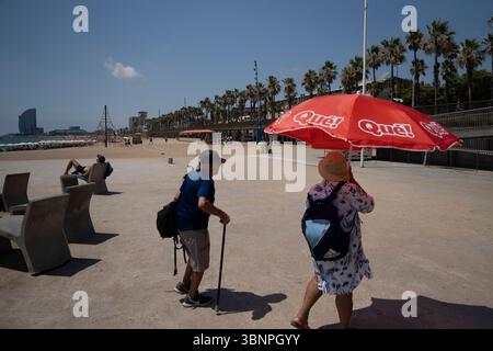 Barcelona, Spanien. Juli 2025. Touristen schützen sich vor der Sonne unter einem Sonnenschirm am Strand von Barcelona. Quelle: SOPA Images Limited/Alamy Live News Stockfoto