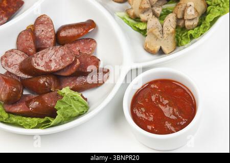 Geschnittene Würstchen, gebraten mit Gemüse und Gewürzen, isoliert auf weißem Hintergrund Stockfoto