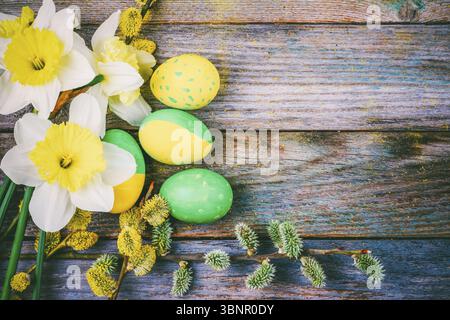 Ostern Zusammensetzung der Narzisse Blume blühen willow Twigs und Ostereier mit einem Muster aus gelben und grünen Farbe auf einer hölzernen retro Hintergrund wit Stockfoto