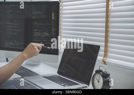 Programmierung der Softwareanwendung. Programmierer schreibt Programmcode mit zwei Monitoren und arbeitet mit Hacker an einer neuen Software Stockfoto