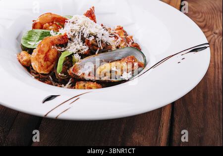 Stillleben, Schwarze Spaghetti mit Meeresfrüchten auf weißem Teller Stockfoto