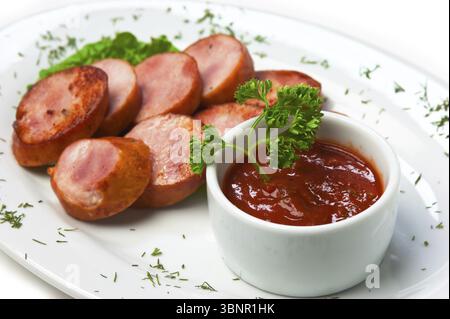 Geschnittene Würstchen, gebraten mit Gemüse und Gewürzen, isoliert auf weißem Hintergrund Stockfoto
