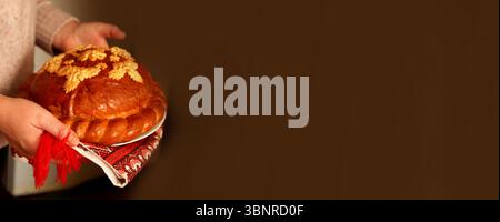 Ein wunderschönes Korovai, ukrainisches Zeremonienbrot, mit kompliziertem Design und traditionellem Muster, präsentiert auf einem Banner mit viel Kopierraum, Symbolen Stockfoto