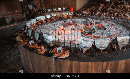 In Bagdad werden verschiedene Fleischgerichte über einem offenen Feuer gegrillt, umgeben von Freunden, die das fest genießen. Stockfoto