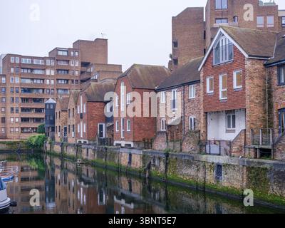 Vereinigtes Königreich, London, 13. Juli 2025. Wohnhäuser am Kanal in East London mit ihren Reflexen auf dem Wasser auf einer ruhigen und bewölkten Winde Stockfoto