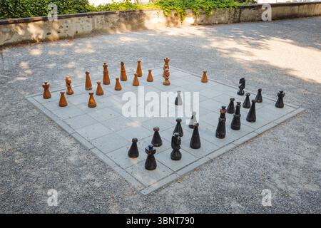 Großes, öffentliches Schachbrett im Park mit riesigen Holzstücken. Von oben nach unten, Weitwinkelblick, sonniger Sommertag, keine Leute Stockfoto