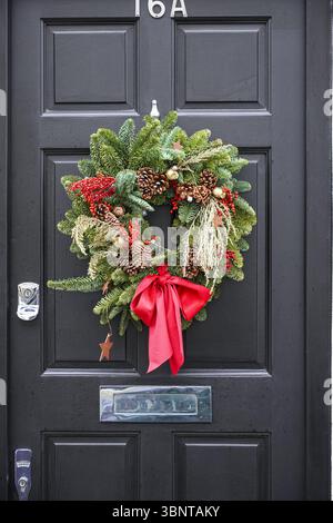 Ein dekorativer Weihnachtskranz hängt an der Haustür eines Hauses in Kensington, London, England, Großbritannien Stockfoto