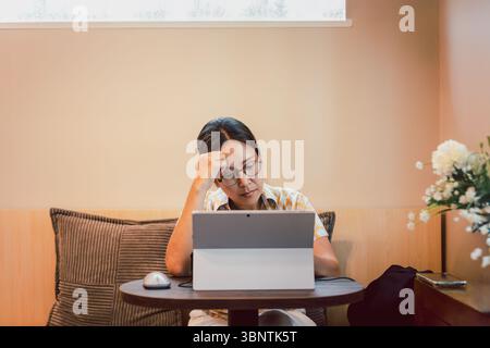Eine gestresste Frau, die gerne ihren Kopf hält, während sie am Laptop arbeitet. Stockfoto