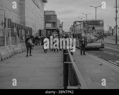Vereinigtes Königreich, London, 11. Dezember 2024. Fußgänger laufen während der Hauptverkehrszeit entlang der London Bridge mit einem Doppeldeckerbus im Hintergrund. Stockfoto