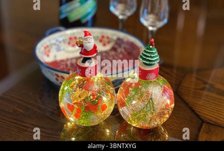 Glühende Weihnachtskugeln, reflektierend auf einem Tisch Stockfoto