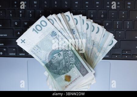 Polnische 100-Zloty-Banknoten werden auf Einer Laptop-Tastatur verteilt und symbolisieren Online-Banking, digitale Finanzen, E-Commerce oder Finanzplanung im Modus Stockfoto